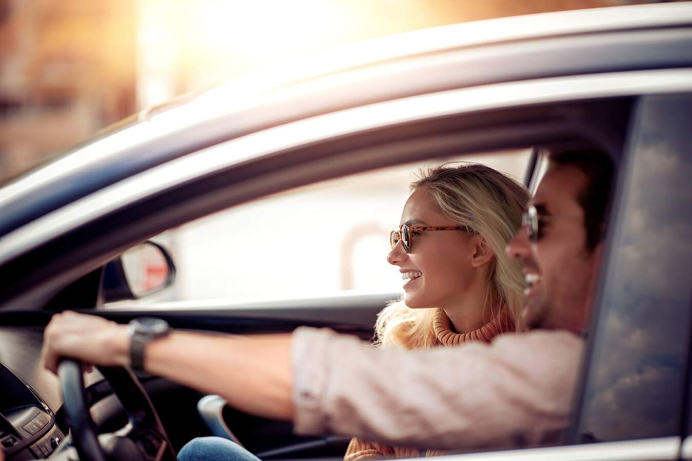 Happy couple driving clean car after Rainforest Carwash visit